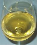 Deatilní pohled na výraznou zlato žlutou barvu vína ve sklenici.