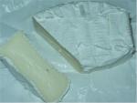 Řez sýrem GÉRAMONT s bílou plísní na povrchu.